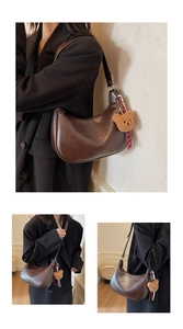 Close-up of dark brown crescent bag featuring plush bear charm and striped strap detail