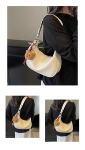 Detail of white leather hobo bag with teddy bear charm and decorative red white scarf