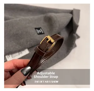 Close-up of adjustable brown leather shoulder strap with gold-tone buckle and neat stitching