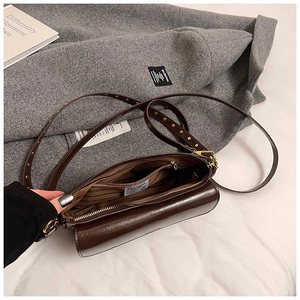Detailed view of dark brown crossbody bag interior with striped lining and golden clasp