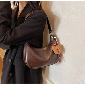Detail of vintage brown leather hobo bag with teddy bear charm and logo embossing