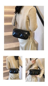 Detail of black patent leather shoulder bag with elegant pleated design and gold hardware