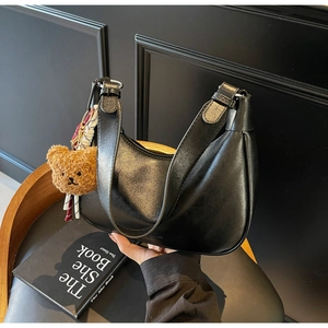 Detail of black matte crescent underarm bag with a brown teddy bear pendant charm