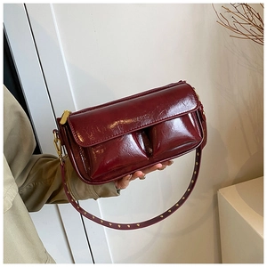 Detail of dark red glossy shoulder bag with PARIS engraving and gold studded strap