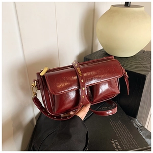 Detail of burgundy glossy leather handbag with PARIS logo strap and gold metal rivets