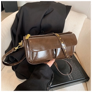 Detail of vintage brown oily leather crossbody bag with double front pockets and gold studs