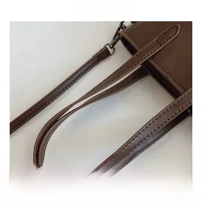 Detail shot of the brown leather handbag handle with precise stitching and metal hooks