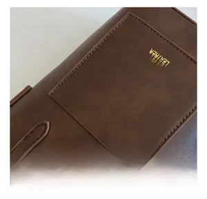 Close-up of dark brown leather handbag with fine stitching and gold lettering detail