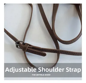 Detail view of brown leather adjustable shoulder strap with dark gunmetal buckle