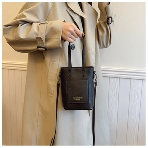 Detail of minimalist black leather mini tote with shoulder strap and front pocket