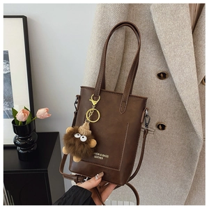 Detail of vintage brown PU leather square bag with functional front pocket and plush charm