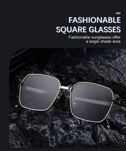Détail de lunettes de soleil carrées en métal doré avec verres gris sur fond de roche