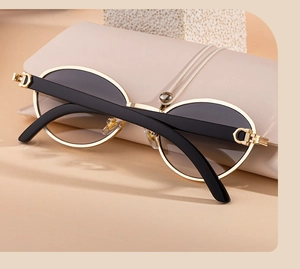 Detail of vintage oval gold metal frame sunglasses with signature C-shaped hinge and beige case