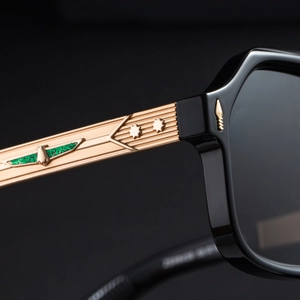 Macro detail of black sunglasses with embossed gold metal temples and star accents
