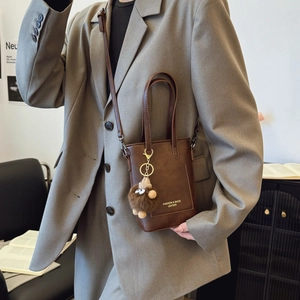 Vintage brown leather crossbody bag with dual handles and plush bear charm decoration