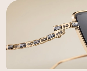 Detailed macro shot of golden metal sunglasses temples with grey crystal inlay