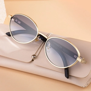Chic oval gold metal frame sunglasses with grey lenses on beige leather case