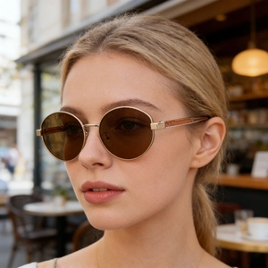 Detail of vintage round sunglasses with gold metal frames and textured temples on a model