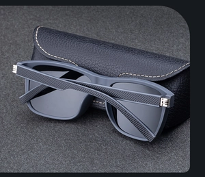Detail of gray matte sunglasses frames and textured leather case with precise stitching