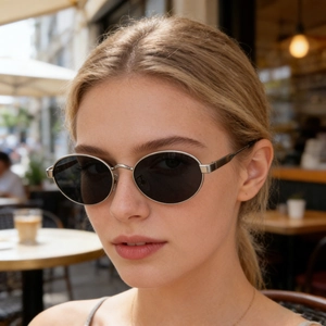 Détail de lunettes de soleil ovales avec monture en métal argenté et verres noirs