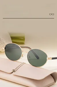 Detail view of oval polarized sunglasses with gold metal frame and a pink leather case