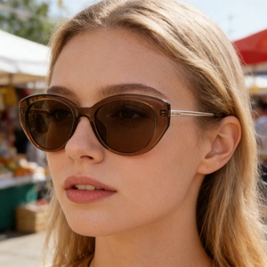 Dettaglio degli occhiali da sole cat-eye con montatura marrone e stanghette in metallo