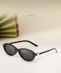 Détail de lunettes de soleil ovales montrant la monture noire TR et les charnières en métal doré