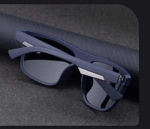 Close-up of matte dark blue square sunglasses with silver metal trim on textured background