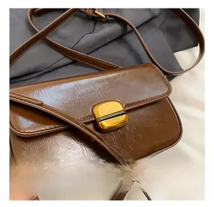 Detail of vintage brown oil wax leather bag featuring a gold oval twist lock buckle