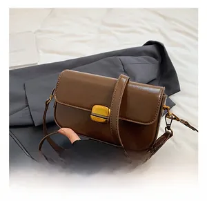 Close-up of retro dark brown leather crossbody bag with vintage golden metal buckle