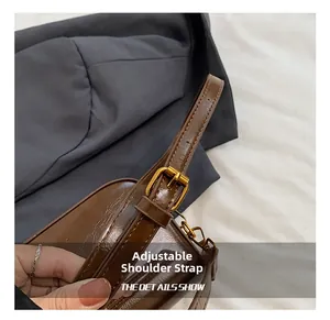 Detailed macro of the adjustable shoulder strap with vintage golden buckle on brown bag