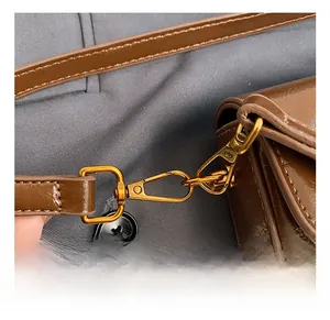 Macro detail of high-quality gold metal hook on a brown vintage crossbody bag