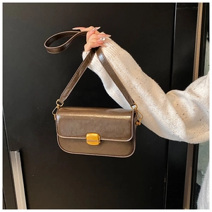 Détail du sac bandoulière en cuir marron foncé brillant avec chaîne et boucle dorée