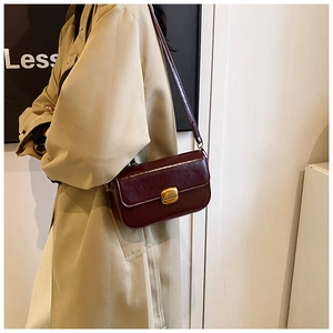 Détail du sac à rabat rectangulaire bordeaux avec cuir brillant et boucle dorée