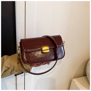 Détail du petit sac bandoulière rétro rouge bordeaux avec boucle dorée et texture cuir