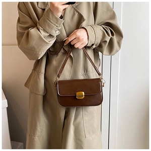 Détail d'un sac bandoulière minimaliste en cuir marron café avec boucle en métal doré
