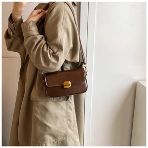 Détail de la texture en cuir synthétique marron foncé et boucle dorée du sac à bandoulière