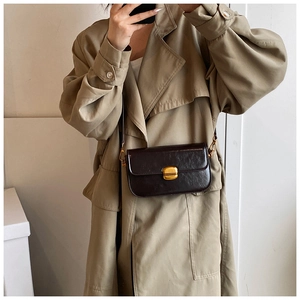 Détail du sac bandoulière en cuir marron foncé avec un fermoir métallique doré carré