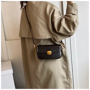 Vue détaillée du sac bandoulière en cuir marron foncé avec boucle dorée sur mannequin