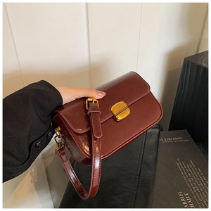 Gros plan d'un sac à bandoulière bordeaux vintage avec texture brillante et boucle dorée