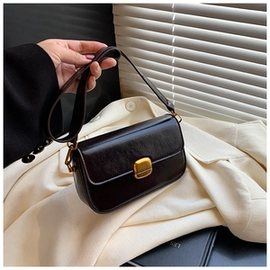 Détail d'un sac carré en cuir ciré marron foncé avec un fermoir en métal doré chic