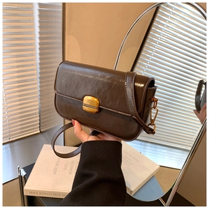 Détail de la texture en cuir synthétique marron foncé et du fermoir doré sur le sac carré