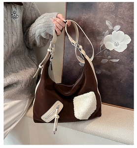 Detail of dark brown hobo bag with plush white patch and beige zipper decoration