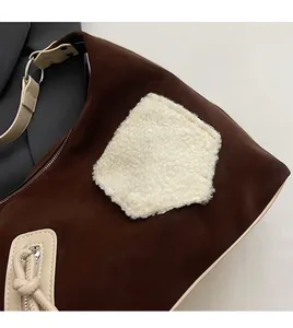 Detail of dark brown suede bag with white fleece patchwork and silver hardware