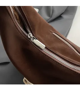 Detailed macro view of the smooth silver metal zipper on a brown leather tote bag