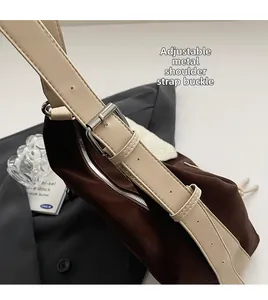 Detail of the metal hardware buckle and adjustable leather strap on a brown shoulder bag