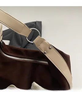 Detail of silver metal rings and double rivets on a brown fabric shoulder bag