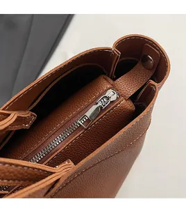 Detail of smooth silver zipper and contrast stitching on brown pebble leather bag