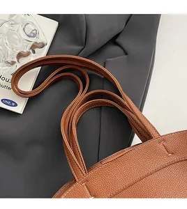 Detail of brown leather tote featuring lychee texture and white contrast stitching