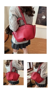 Detailed view of red pebble leather tote bag with contrast stitching and shoulder strap